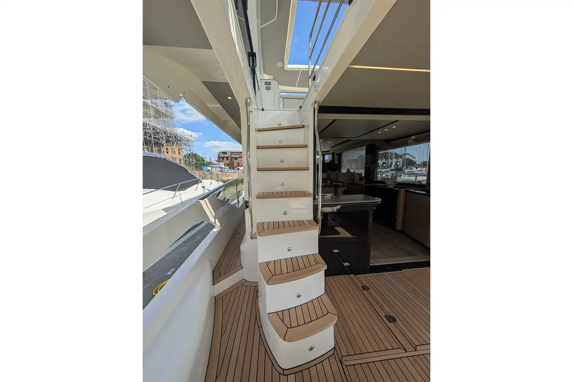 Modern boat staircase leading to an indoor space, featuring wooden steps and a stylish design, with marina views visible.